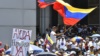 Сторонник Хуана Гуайдо держит национальный флаг Венесуэлы у знака с надписью «Гуманитарная помощь сейчас!» во время демонстрации в Каракасе 6 апреля 2019 года