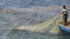 Работник рыбного хозяйства тянет сеть во время ловли кефали в водах Черного моря возле полуострова Тарханкут, Крым 3 октября 2017 года